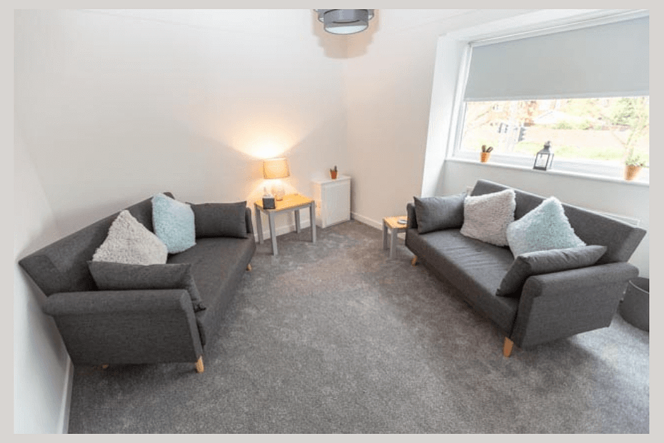 A serene therapy room featuring comfortable seating, warm lighting, and calming decor, creating an inviting atmosphere for therapy sessions.