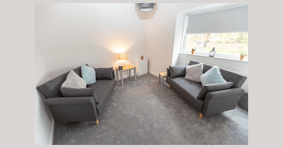 A serene therapy room featuring comfortable seating, warm lighting, and calming decor, creating an inviting atmosphere for therapy sessions.