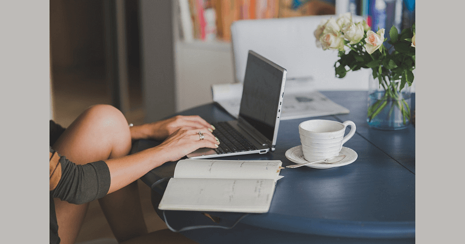 Person sat at desk with laptop open, notepad beside them